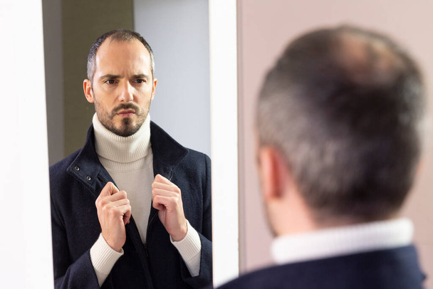 A man looking at himself in the mirror for self-confidence. - Foto, Imagen