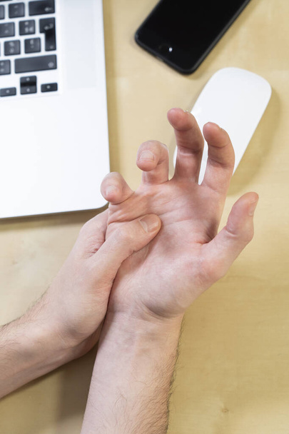 Close-up of a man's hand experiencing pain due to prolonged use of the mouse. - 写真・画像