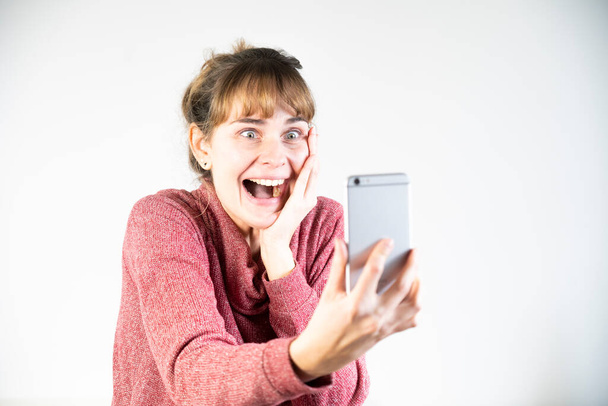 Крайне радостная женщина при виде своего нового смартфона. - Фото, изображение