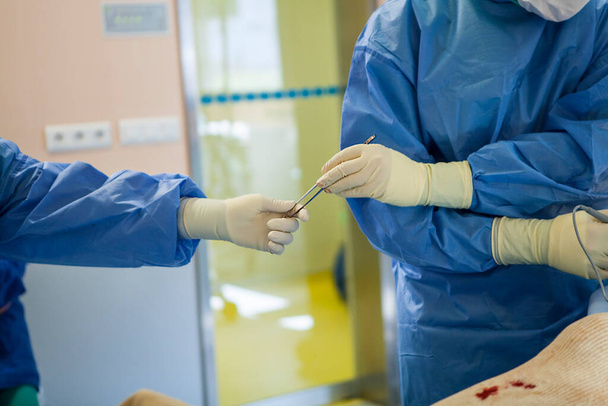 A nurse gives a tool to the surgeon in the operating room of an orthopedic surgery department. - Photo, Image