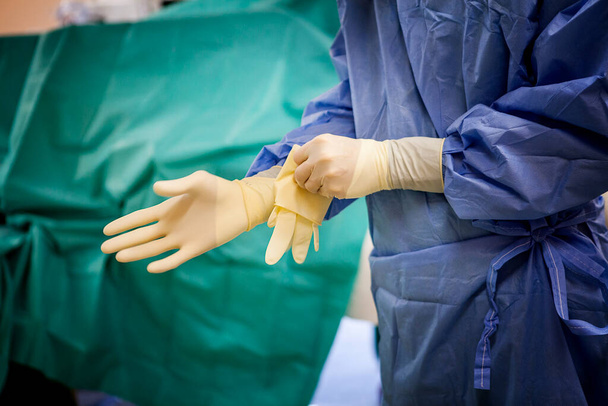 Медсестра надевает перчатки в операционной больницы.. - Фото, изображение