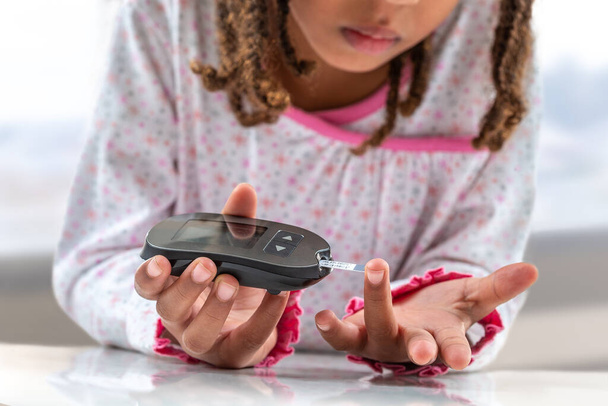 Concepto niños diabetes niños con glucosímetro aprender a controlar el nivel de azúcar en la sangre en el hogar. Aprende a usar un glucosímetro. Educación de los niños diabéticos, en el hospital
 - Foto, imagen