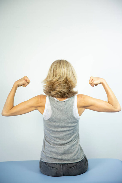 Woman looking at her muscles. - 写真・画像