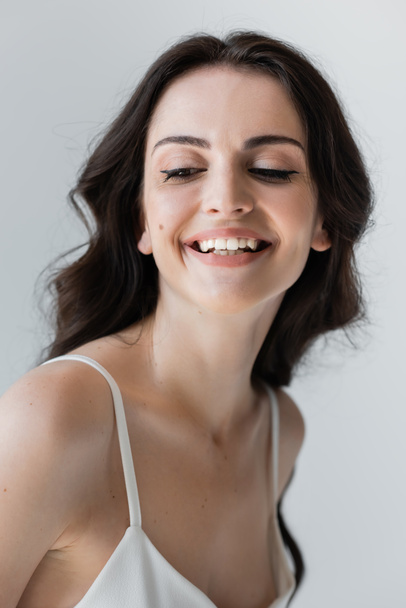 Smiling woman with makeup looking away isolated on grey  - Foto, Imagem
