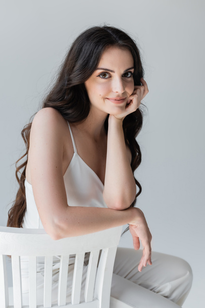Portrait of pretty woman in white clothes sitting on chair isolated on grey  - Foto, Imagem