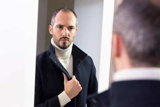 A man looking at himself in the mirror for self-confidence. - Photo, image