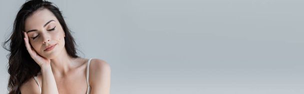 Brunette woman with closed eyes standing isolated on grey, banner  - Foto, imagen