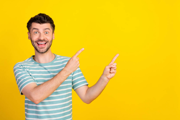 Portrait photo of young attractive guy excited crazy pointing empty space advertisement isolated on yellow color background. - Фото, зображення