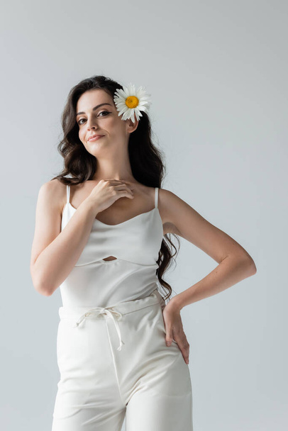 Smiling model in white clothes and chamomile in hair isolated on grey  - Foto, immagini