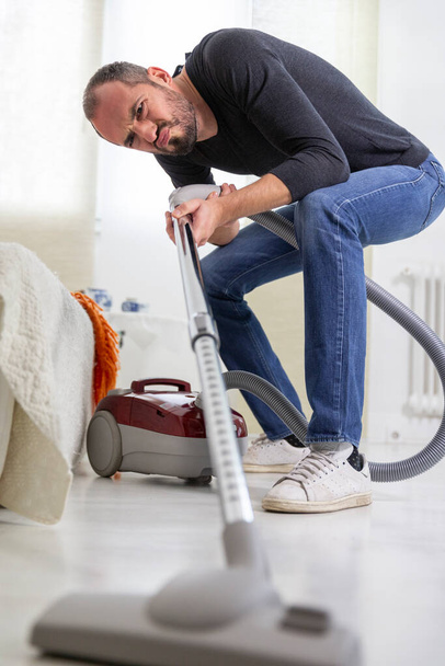 A man vacuuming at home - Фото, изображение