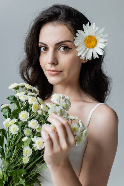 Portrait of young woman holding chamomiles isolated on grey  - Foto, Imagem