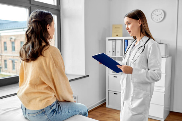 medicine, healthcare and people concept - female doctor with clipboard talking to woman patient at hospital - Foto, imagen