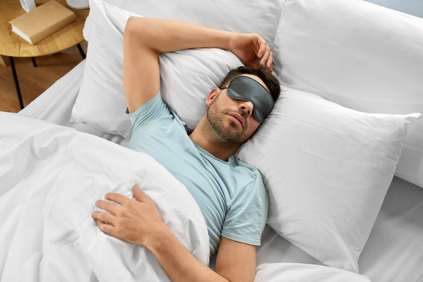 people, bedtime and rest concept - man in eye mask sleeping in bed at home, top view - Foto, Imagem