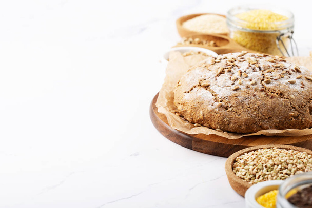 Ancient grain food. Bread Gluten free, Healthy eating, dieting, balanced food concept. Cereals gluten-free, millet, quinoa, polenta, buckwheat, flax seeds, sunflower seeds on white background. - Photo, Image