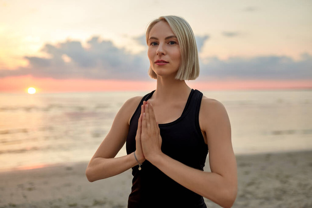 yoga, mindfulness and meditation concept - woman meditating on beach over sunset - Valokuva, kuva