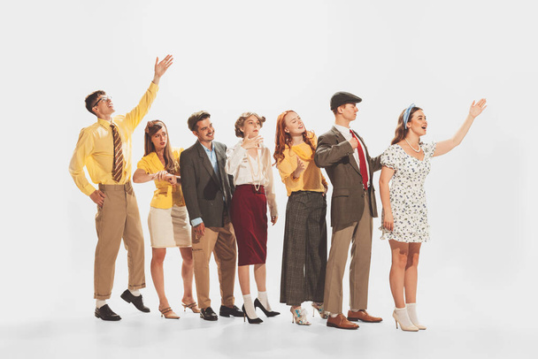 Group of young stylish people standing in a line, talking, expressing ideas isolated over white studio background. Voting process. Concept of retro fashion, style, youth culture, emotions, beauty, ad - Valokuva, kuva