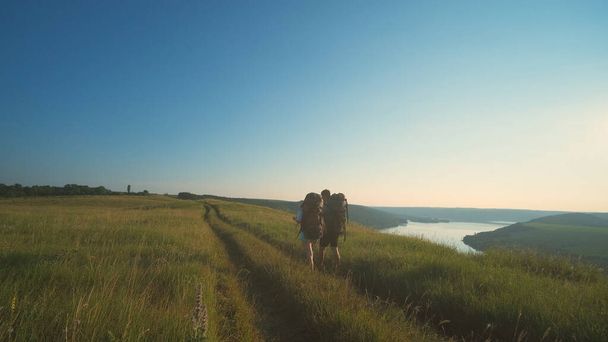 The two travelers walking with backpacks on a blue sky background - 写真・画像