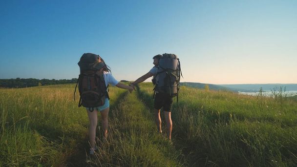 The man and woman walking with backpacks on a blue sky background - Photo, image