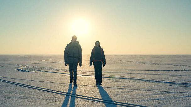 Две экспедиции с рюкзаками идут по снежному полю - Фото, изображение