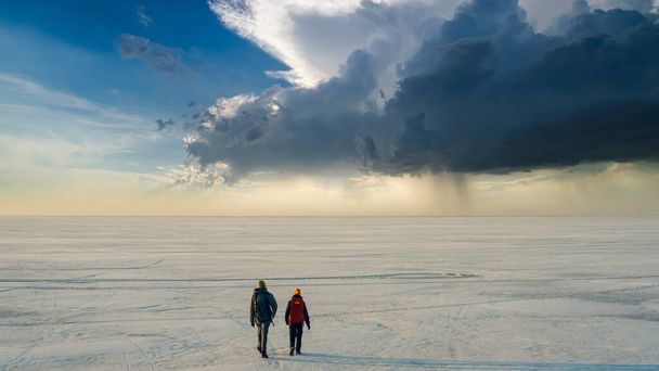 The two people walking through the endless snow field - Fotografie, Obrázek