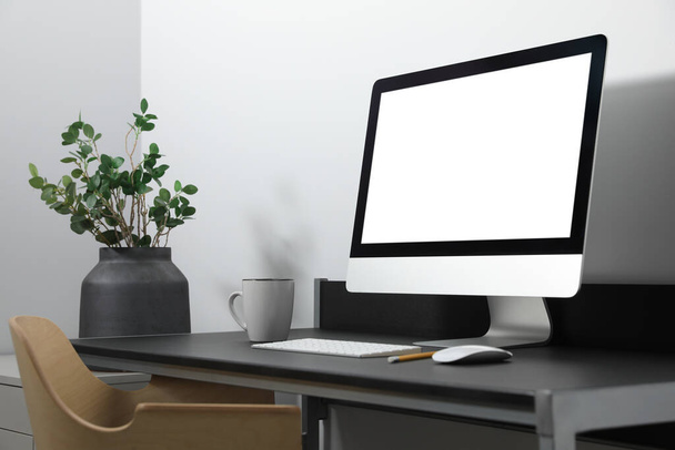 Modern computer with blank screen on black table indoors. Mockup for design - Photo, image