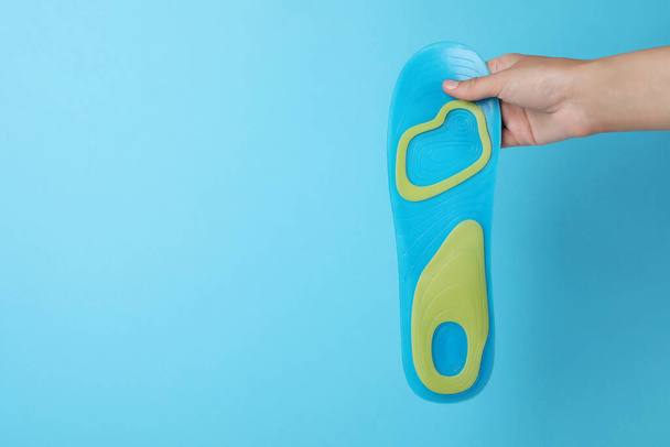 Woman holding orthopedic insole on light blue background, closeup. Space for text - Fotó, kép