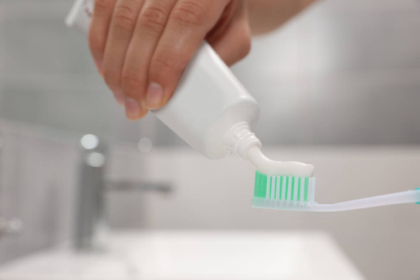 Woman applying toothpaste on brush in bathroom, closeup - Foto, Bild