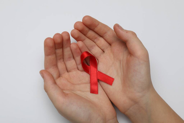 Little girl holding red ribbon on white background, closeup. AIDS disease awareness - Fotoğraf, Görsel
