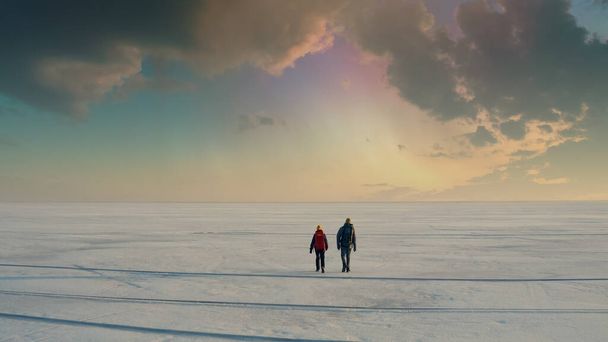 The two tourists going through the snow field against beautiful sky - Fotó, kép