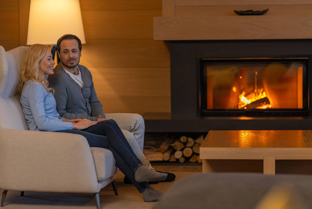 The man and woman sitting near the fireplace  - Foto, imagen