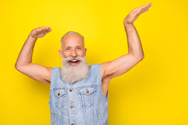 Photo of handsome charming man pensioner dressed denim dancing having fun isolated yellow color background. - Foto, Imagen