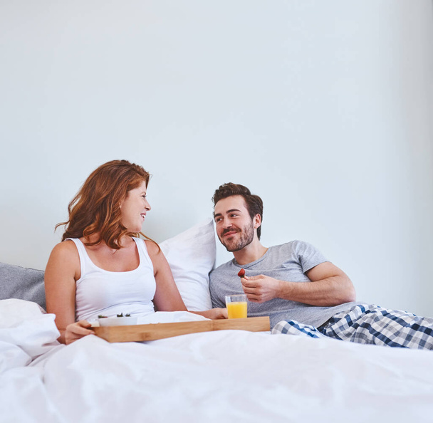 Насолоджуйтесь сніданком зі стороною солодкої розмови. пара насолоджується сніданком в ліжку разом вдома
 - Фото, зображення
