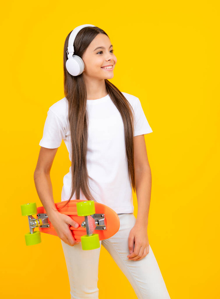 Teen girl 12, 13, 14 years old with skateboard over studio background. Cool modern teenager in stylish clothes. Teenagers lifestyle, casual youth culture. Happy teenager portrait - Photo, image
