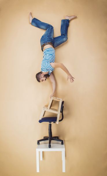 Man standing on a pile of chairs - Φωτογραφία, εικόνα