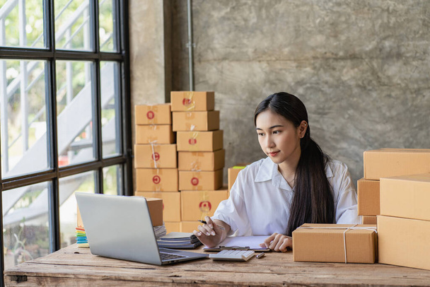 Starting a Successful Small Business Owner Independent Asian female saleswoman using laptop to check and Prepare parcel boxes to send to customers, SME entrepreneurs, online business ideas - Foto, immagini