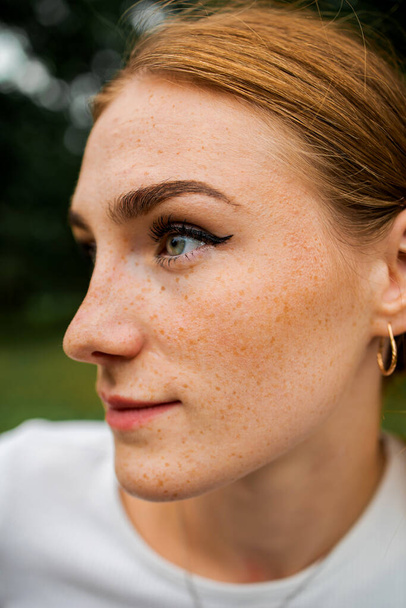 Close-up face of a young ginger ginger freckled woman with red hair and perfect healthy freckled skin, looking at the camera with a pretty cute smile - Foto, imagen