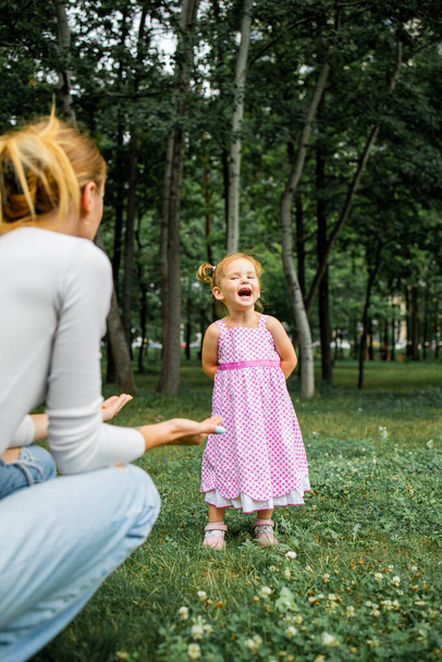Beautiful young mother with her two years old daughter playing on the grass - Fotografie, Obrázek