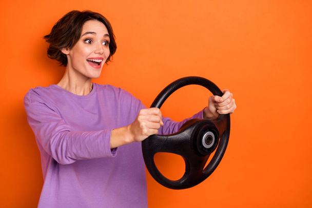 Profile photo of impressed positive girl hold wheel look excited empty space isolated on orange color background. - Fotó, kép