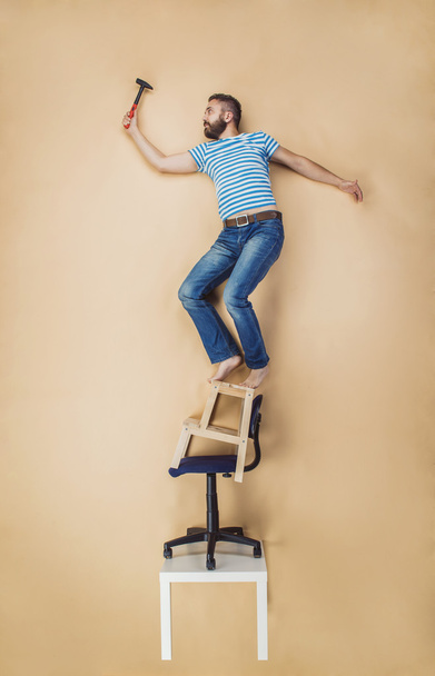 Handyman standing on a pile of chairs - Foto, Bild