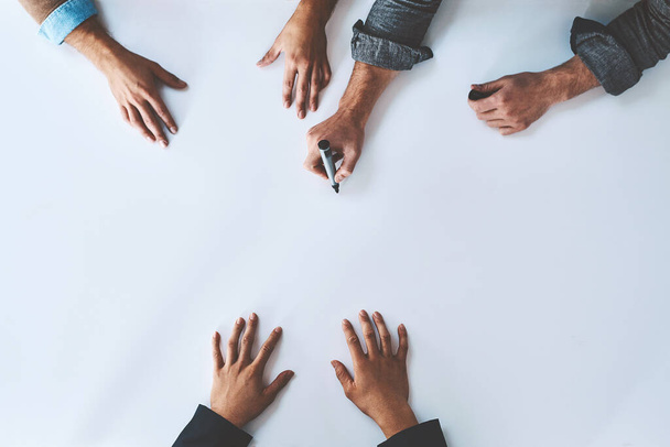 Business people writing on white paper in meeting, planning a marketing strategy and writing creative ideas together from above. Top view of hands of team of designers drawing a design on blank page. - Zdjęcie, obraz