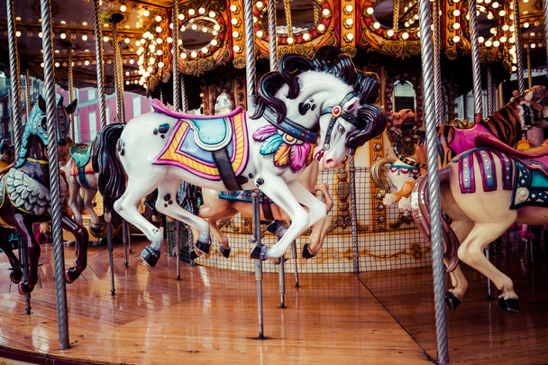 altes französisches Karussell in einem Ferienpark. Drei Pferde und ein Flugzeug auf einem traditionellen Jahrmarkt-Oldtimer-Karussell. Karussell mit Pferden.  - Foto, Bild