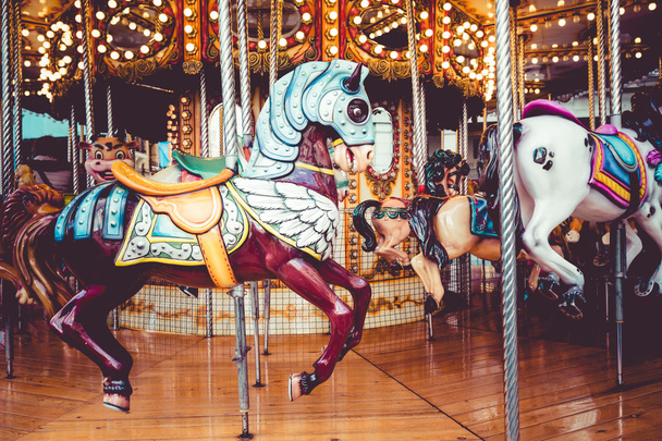Oude Franse carrousel in een vakantiepark. Drie paarden en vliegtuig op een traditionele kermis vintage carrousel. Merry-go-round met paarden.  - Foto, afbeelding