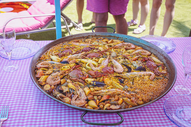 Traditional paella for the whole family. Outdoor dining with the family in the summer. Delicious traditional paella of Spanish cuisine - Valokuva, kuva