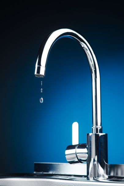 robinet mélangeur avec gouttes d'eau, fond bleu
 - Photo, image