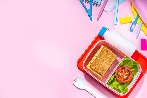 Healthy school meal, back to school concept. Children packed lunch box with balanced diet snack food - yogurt, cereal toast sandwich, apple, fresh vegetable salad, high-colored bright background - Zdjęcie, obraz