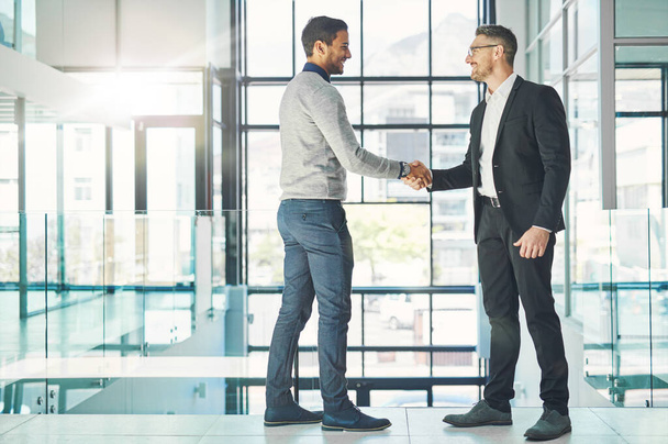 Handshake, teamwork and working together with corporate business men and colleagues at work as a team. Making a deal during a meeting, greeting and coming to an agreement in a modern office. - Photo, Image