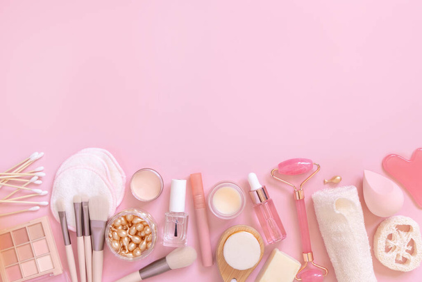 Skin care and makeup products on light pink, top view, copy space. Flat lay with natural beauty products and decorative cosmetics. Everyday woman face care routine  - Photo, Image