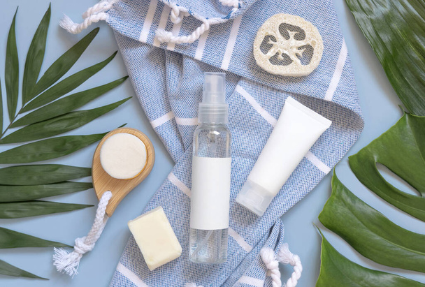 Transparent Refillable spray dispenser bottle and white cream tube on blue bath towel near body care accessories top view, copy space. Packaging mockup. Natural eco friendly Cosmetics - Foto, immagini