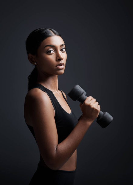 Taking your health seriously is the best form of self-love. Studio portrait of a young sportswoman doing dumbbell exercises against a gray background - Foto, Imagen
