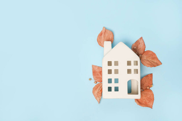 Toy white house and autumn leaves on blue background. Thanksgiving banner, copy space. Hygge mood, change of seasons concept. Hello Autumn - Foto, immagini